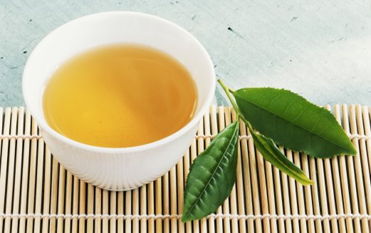 Tea bowl and tea leaves on bamboo mat, close-up